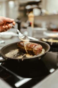 une personne cuisine un morceau de viande dans un bac dans l'établissement Villa Bavaria, à Merano