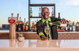 Un uomo che versa un bicchiere di vino in un bar di Holiday Inn Johannesburg-Rosebank, an IHG Hotel a Johannesburg