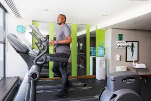 Un uomo in piedi su un tapis roulant in palestra di Holiday Inn Johannesburg-Rosebank, an IHG Hotel a Johannesburg