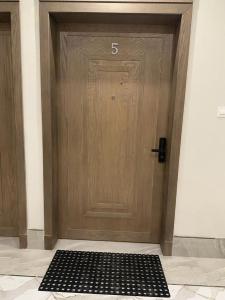 una puerta de madera con una alfombra negra delante de ella en شقة عائلية خاصة مفروشة في الخبر 1, en Al Khobar