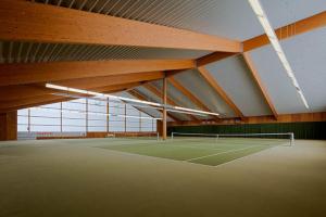 a tennis court in a large building with a tennis racket at Sporthotel Malchow Hotel Garni HP ist möglich in Malchow