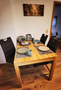 uma mesa de madeira com cadeiras e pratos em Ferienwohnung im Starenweg em Blankenburg