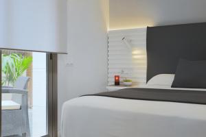 a bedroom with a white bed and a window at Hotel Sitges in Sitges