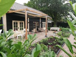 une terrasse arrière avec une pergola en bois dans l'établissement Logeren bij De Soerensesteeg, à Uddel