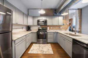 una cucina con armadietti bianchi ed elettrodomestici in acciaio inossidabile di City Escape 2BR Steps to TQL near OTR and Downtown a Cincinnati