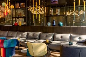 sala de estar con sofá, sillas y lámparas de araña en Motel One Wien-Prater, en Viena