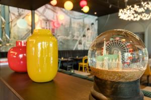 una bola de nieve de cristal sentada en una mesa junto a un jarrón amarillo en Motel One Wien-Prater, en Viena