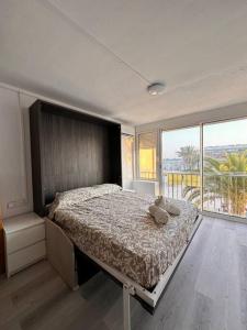 a bedroom with a bed and a large window at A pie de PLAYA in La Pineda