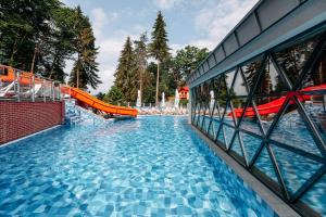 een groot zwembad met een oranje glijbaan bij HOTEL CRYSTAL WELLNESS & SPA superior in Sovata