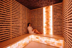 een vrouw zit in een sauna bij HOTEL CRYSTAL WELLNESS & SPA superior in Sovata