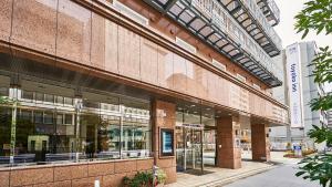 un gran edificio de ladrillo con ventanas de cristal en una calle en Toyoko Inn Osaka Tenjinbashi-suji Rokuchome, en Osaka