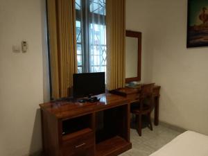 Zimmer mit einem Schreibtisch, einem TV und einem Spiegel in der Unterkunft RedDoorz at Griya Cemara Homestay Yogyakarta in Yogyakarta