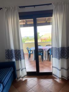 ein Wohnzimmer mit einer Glasschiebetür und einem Tisch in der Unterkunft Case Vacanze Villa Rosita in San Teodoro