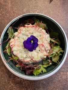 a bowl of salad with a purple flower on it at Salon Boyer in Épernay