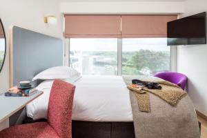 een slaapkamer met een bed, een bureau en een raam bij Bedruthan Hotel & Spa in Newquay