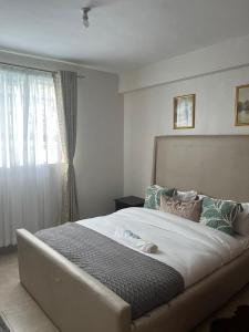 una camera da letto con un grande letto e una finestra di Zoe Homes Oak Villa Apartment 1 and 2 Bedroom 201 a Kericho