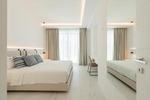 a white bedroom with two beds and a window at Arcs Suites & Residences in Mýkonos City