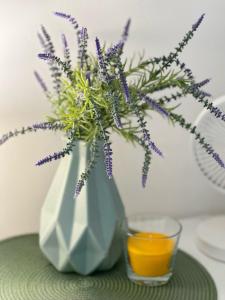 un vase avec des fleurs violettes à côté d'un verre dans l'établissement Anielewicza 26 Rooms, à Varsovie