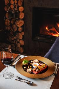 einen Teller mit Essen auf einem Tisch mit einem Glas Wein in der Unterkunft Hotel Batory in Szczawnica