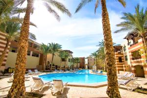 a resort pool with palm trees and lounge chairs at Marina Residence Suites Port Ghalib in Port Ghalib