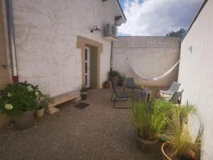 un patio con sedie e piante accanto a un edificio di Le Petit Saugnieu a Colombier-Saugnieu