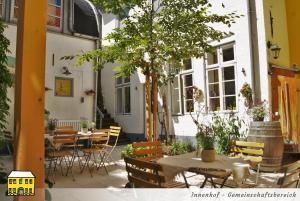 un patio con mesas, sillas y un árbol en Das Gelbe Haus - Drei besondere Ferienwohnungen, en Flensburg