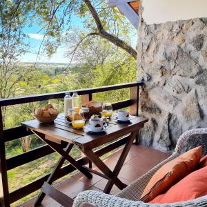 uma mesa com comida e bebidas numa varanda em Aldea de los Pajaros em Villa General Belgrano