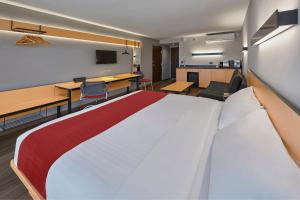 een groot bed in een kamer met een bureau en stoelen bij City Express by Marriott Tepic in Tepic