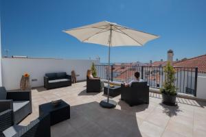 zwei Personen sitzen auf einer Terrasse mit Sonnenschirm in der Unterkunft Sol da Vila in Vila Nova de Milfontes