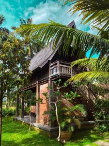 una casa con una palmera delante de ella en Nunu Bali Eco Friendly Retreat, en Canggu