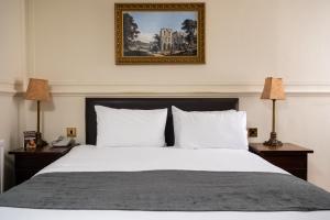 1 dormitorio con 1 cama blanca grande y 2 lámparas en Antelope by Greene King Inns, en Poole