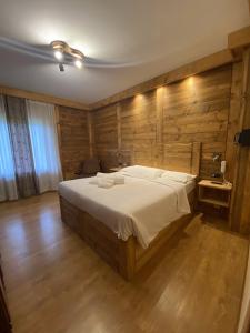 sypialnia z dużym łóżkiem i drewnianymi ścianami w obiekcie Hotel Oasi w mieście San Vito di Cadore