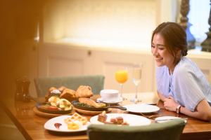 uma mulher sentada à mesa com comida e bebidas em Sheraton Grande Sukhumvit, a Luxury Collection Hotel, Bangkok em Banguecoque