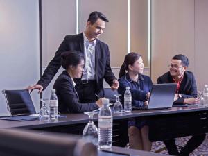 un groupe de personnes assises à une table avec des ordinateurs portables dans l'établissement Pullman Kuching, à Kuching