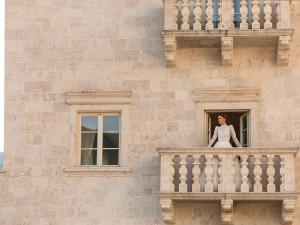 een vrouw die op een balkon van een gebouw staat bij Heritage Grand Perast By Rixos in Perast