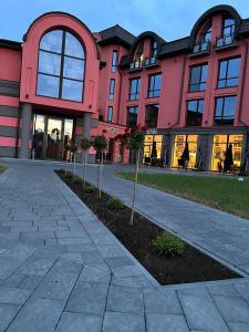 un bâtiment rose avec un arbre devant lui dans l'établissement Hotel Zefir, à Drogobych