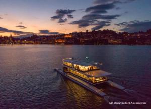 un barco en un gran cuerpo de agua al atardecer en Bürgenstock Hotel & Alpine Spa, en Bürgenstock