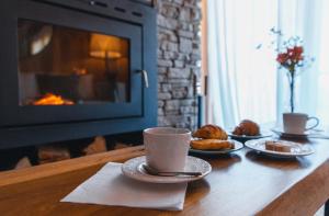 a table with cups and plates of pastries and a fireplace at El Refugio Ski & Summer Lodge in San Martín de los Andes