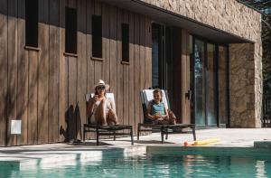 two women sitting in chairs next to a swimming pool at El Refugio Ski & Summer Lodge in San Martín de los Andes