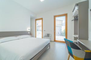 ein weißes Schlafzimmer mit einem Bett und einem Fenster in der Unterkunft Nuova -Luxury Rooms & Apartment- in Olbia