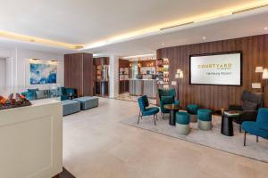 un hall avec des chaises bleues et une salle d'attente dans l'établissement Courtyard by Marriott Hamburg Airport, à Hambourg