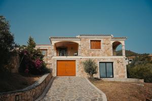 uma casa de pedra com portas cor-de-laranja e uma entrada em Villa Alba Sul Mare em Budoni