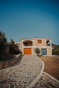 uma entrada de pedra que leva a uma casa com portas laranja em Villa Alba Sul Mare em Budoni