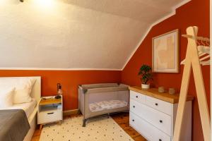 een slaapkamer met oranje muren en een bed en een dressoir bij Moderne Ferienwohnung mit Festungsblick im Zentrum in Königstein an der Elbe