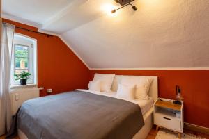 een slaapkamer met een bed met een oranje muur bij Moderne Ferienwohnung mit Festungsblick im Zentrum in Königstein an der Elbe