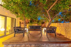 2 Stühle und ein Tisch auf einer Holzterrasse mit einem Baum in der Unterkunft Luxus Villa Skyla mit 5 Schlafzimmern & Meer-Blick in Kaş