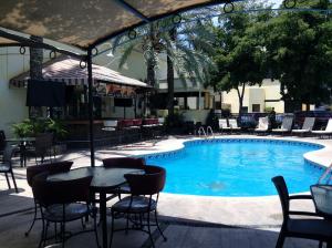 einen Pool mit Stühlen, einem Tisch und Stühlen in der Unterkunft Hotel San Sebastian in Hermosillo