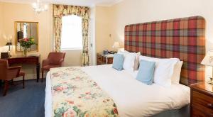 a hotel room with a large bed and a desk at Lindeth Fell Country House in Bowness-on-Windermere