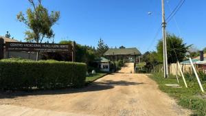 un camino de tierra delante de un edificio con un cartel en Cabañas Huallilemu Norte - Caja Los Andes, en El Quisco