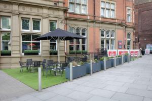 een tafel en stoelen met een parasol voor een gebouw bij Hilton Nottingham Hotel in Nottingham